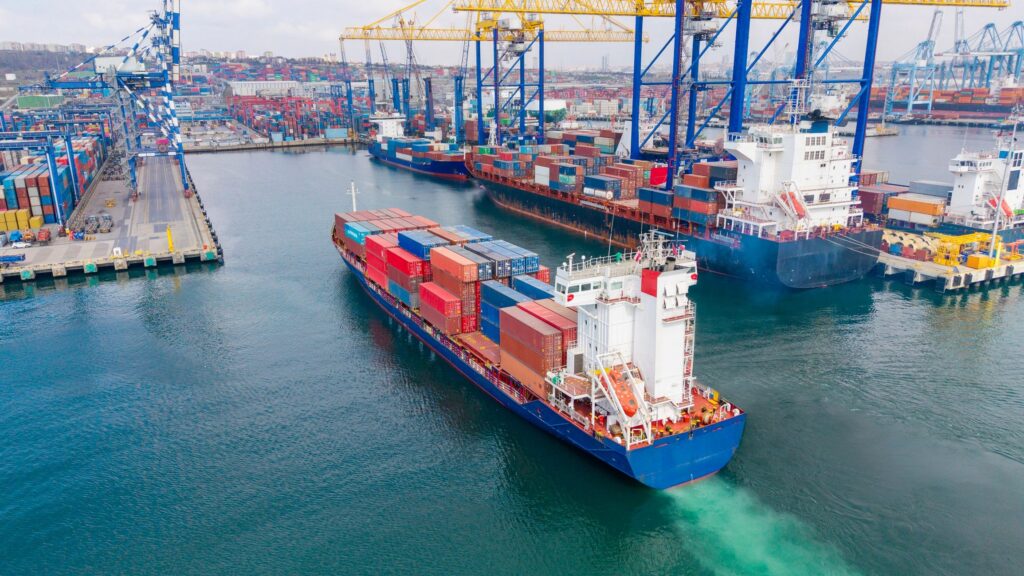 Container ship navigating through busy port terminal